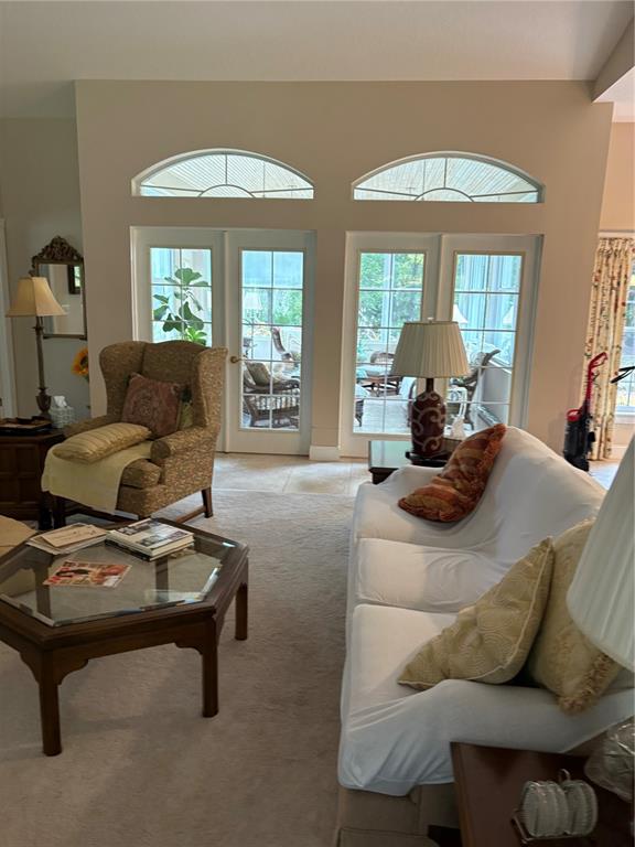 A living room features a white sofa, a patterned armchair, and glass doors to a sunroom — 155 BLAKE STREET, PIERSON, FL