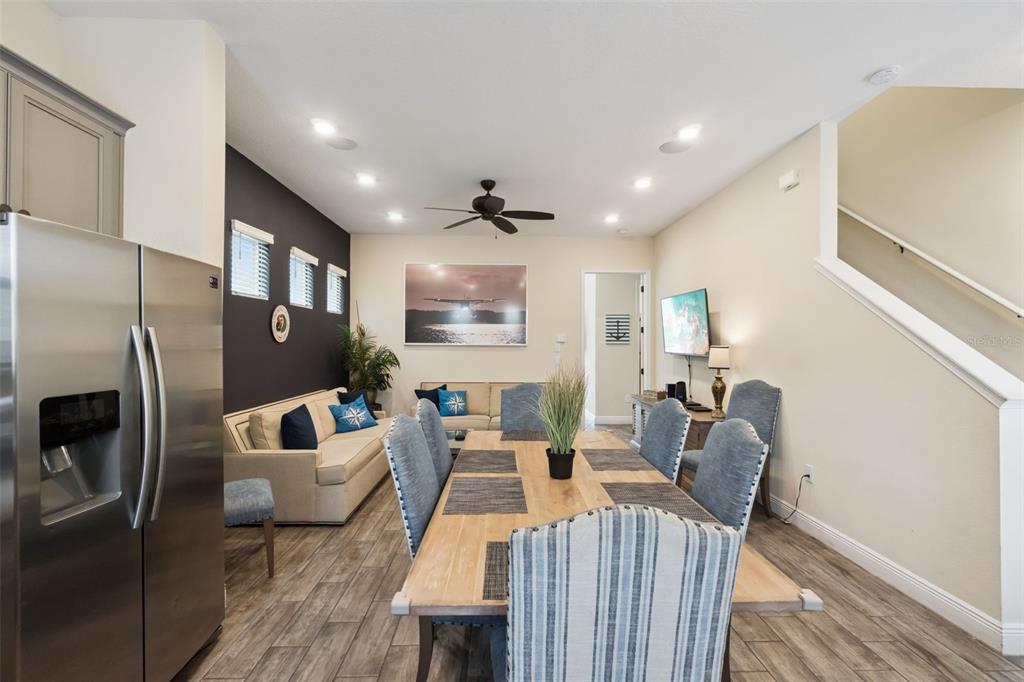 A dining area with a wooden table and chairs sits adjacent to a living room — 8060 DREAMSICLE DRIVE, KISSIMMEE, FL