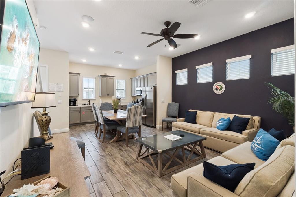 A living room and dining area with tile floors, a dark accent wall, and furniture — 8060 DREAMSICLE DRIVE, KISSIMMEE, FL