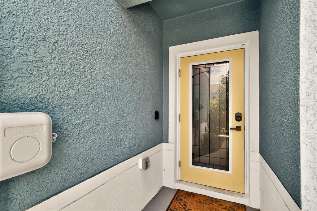 A yellow front door with a glass insert sits on a porch with blue walls — 3083 VICTORIA INLET DRIVE, HOLIDAY, FL
