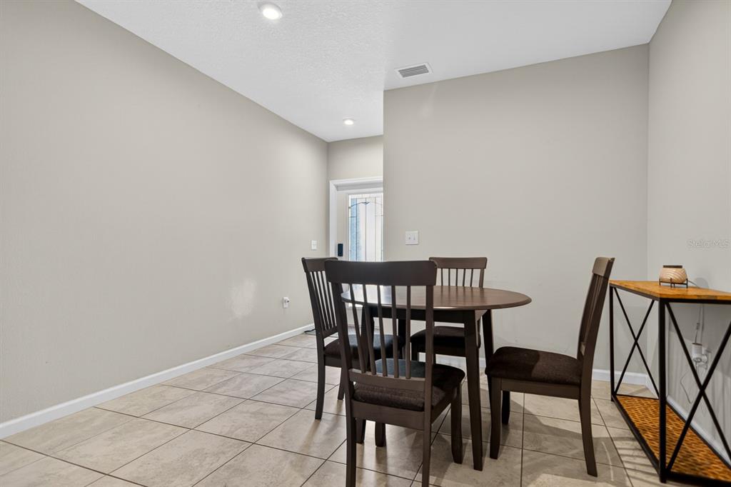 A dining area features a round wooden table with four chairs and tiled flooring — 3083 VICTORIA INLET DRIVE, HOLIDAY, FL