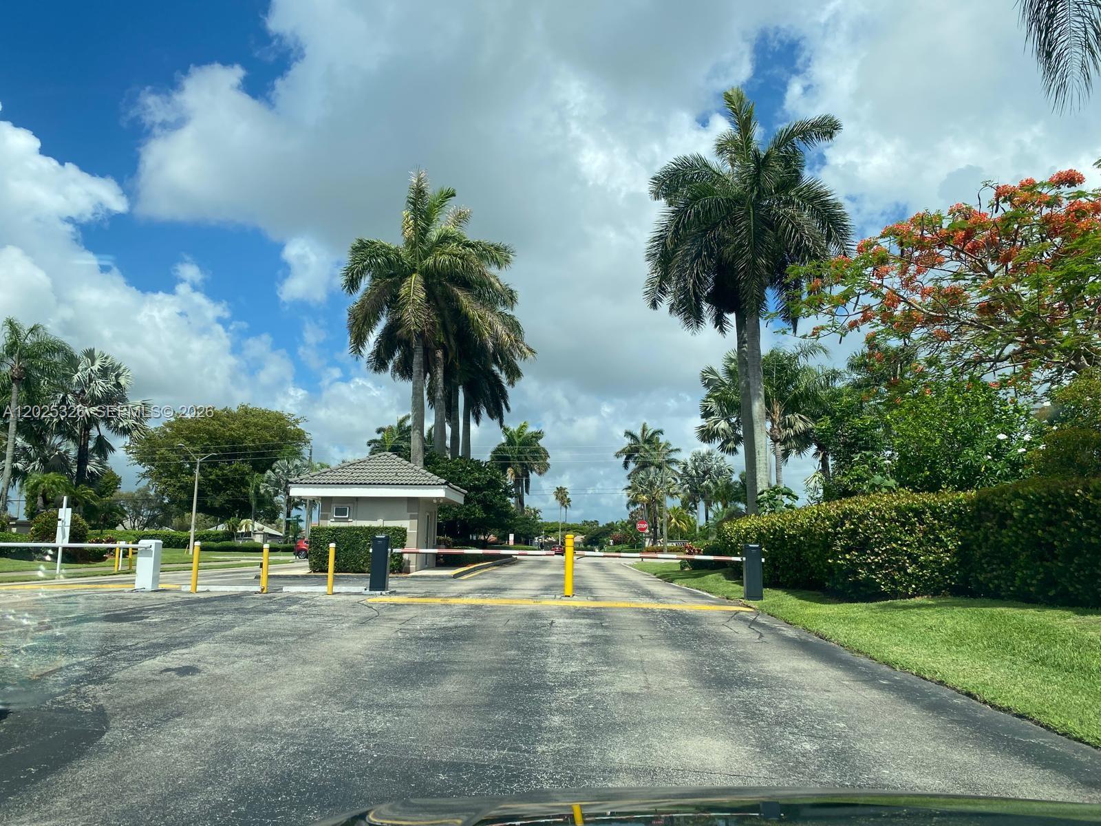 A gated community entrance features a guardhouse, palm trees, and a paved driveway — 3035 SE 7th Pl, Homestead FL 33033, HOMESTEAD, FL