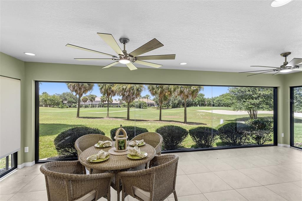 A sunroom with a dining set overlooks a golf course through large glass sliding doors — 1527 GOLDEN RIDGE DRIVE, THE VILLAGES, FL