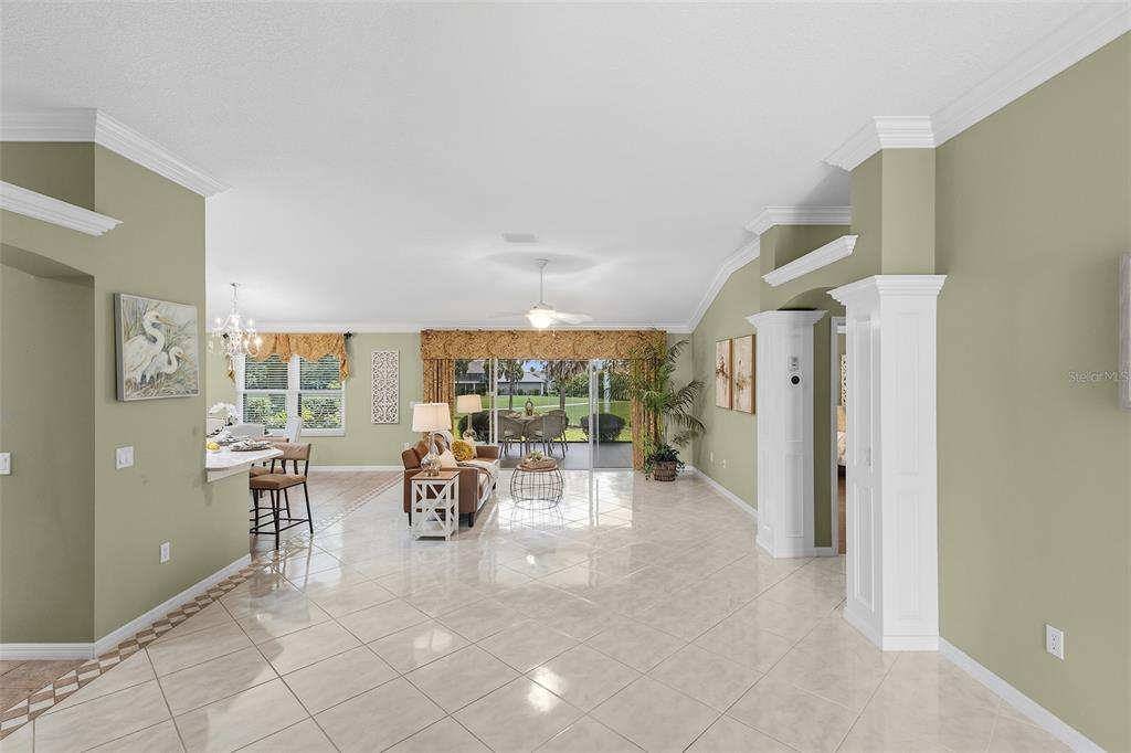 A spacious living room with tile floors, a ceiling fan, and sliding glass doors to outdoors — 1527 GOLDEN RIDGE DRIVE, THE VILLAGES, FL