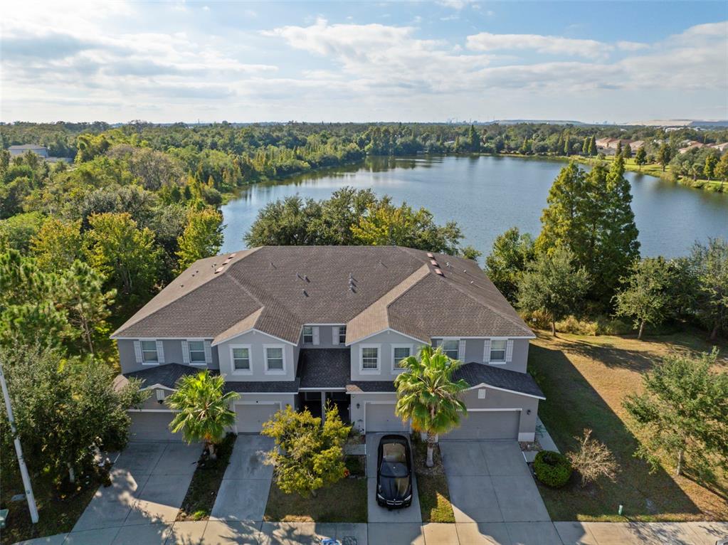 An aerial view shows a two-story duplex house with a lake in the background — 10523 LAKE MONTAUK DRIVE, RIVERVIEW, FL