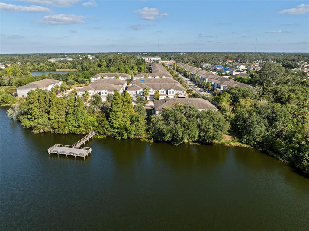 An aerial view shows a residential complex with a wooden dock extending into a lake — 10523 LAKE MONTAUK DRIVE, RIVERVIEW, FL
