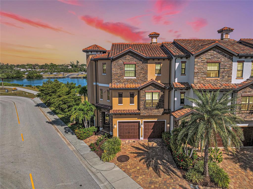An exterior view of a multi-story Mediterranean-style townhouse with a stone facade and tile roof — 205 E VENICE AVENUE, VENICE, FL