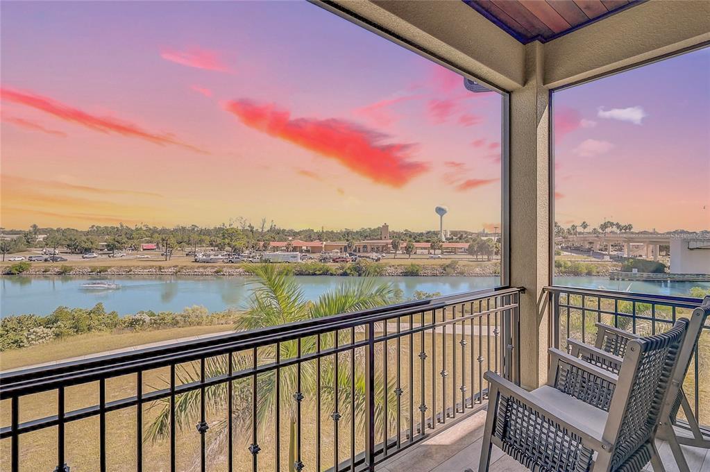 A screened-in balcony overlooks a river with a sunset sky and a distant water tower — 205 E VENICE AVENUE, VENICE, FL