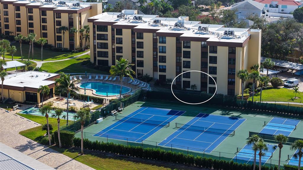 An aerial view of a multi-story apartment building with a swimming pool and tennis courts — 8773 MIDNIGHT PASS ROAD UNIT 102G, SARASOTA, FL