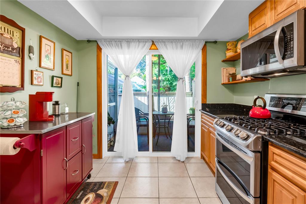 A kitchen with red cabinets, a stainless steel stove, and a sliding glass door — 702 GLASGOW COURT, WINTER SPRINGS, FL