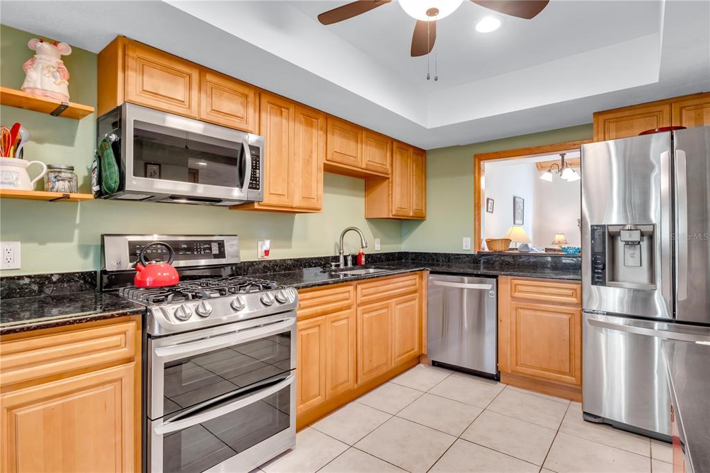 A kitchen with light wood cabinets, stainless steel appliances, and dark granite countertops — 702 GLASGOW COURT, WINTER SPRINGS, FL