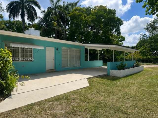 A teal, single-story house features a white front door, a carport, and a planter box — 15280 SW 271st St, Homestead FL 33032, HOMESTEAD, FL