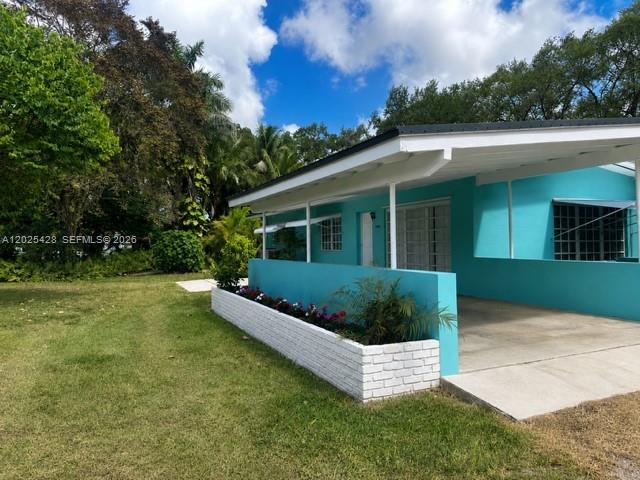A turquoise house features a white brick planter and a covered carport area — 15280 SW 271st St, Homestead FL 33032, HOMESTEAD, FL