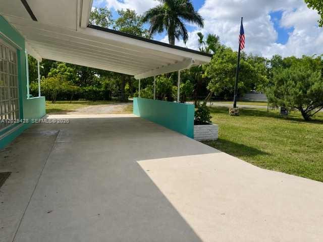 A concrete carport features a teal wall and a metal roof under a blue sky — 15280 SW 271st St, Homestead FL 33032, HOMESTEAD, FL