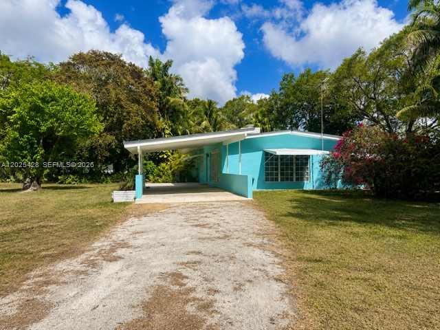 A turquoise single-story house with a carport sits on a grassy lot with trees — 15280 SW 271st St, Homestead FL 33032, HOMESTEAD, FL
