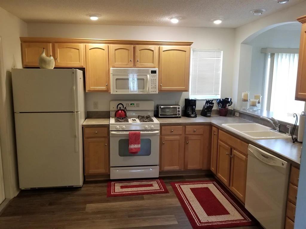A kitchen with light wood cabinets, white appliances, and a double sink on laminate flooring — 1255 VIRGINIA DRIVE, THE VILLAGES, FL