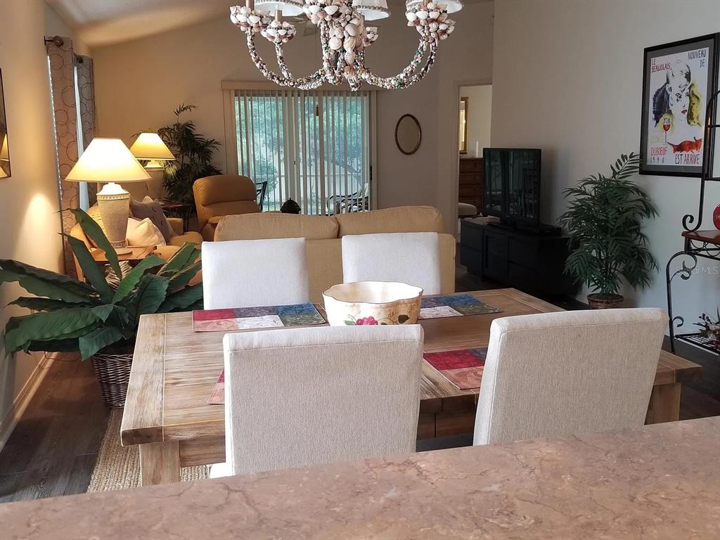 A dining area with a wooden table, upholstered chairs, and a shell chandelier — 1255 VIRGINIA DRIVE, THE VILLAGES, FL