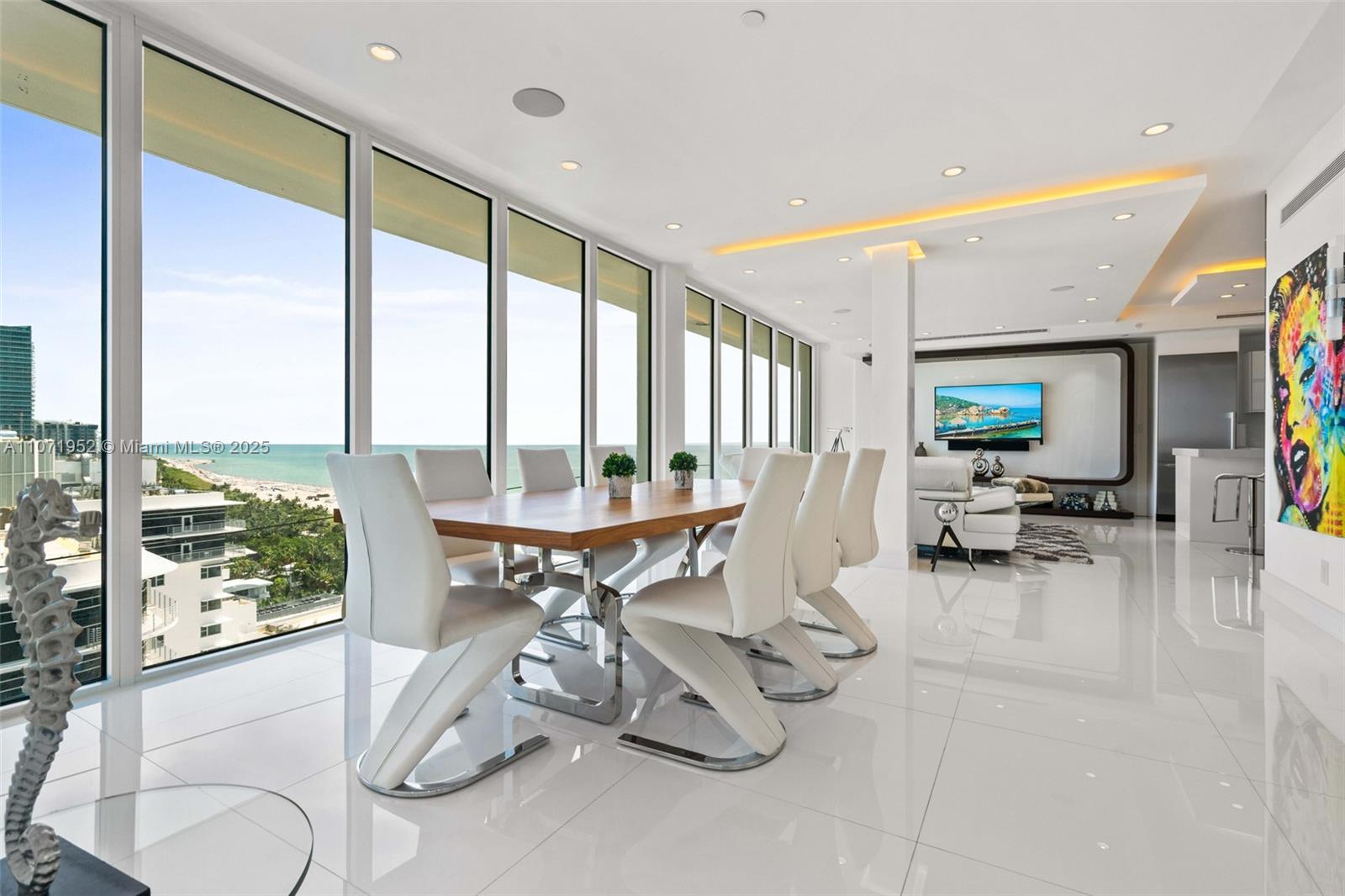 A modern dining room features white tile floors, a wooden table, and floor-to-ceiling ocean views — 100 Lincoln Rd, Miami Beach FL 33139, MIAMI BEACH, FL
