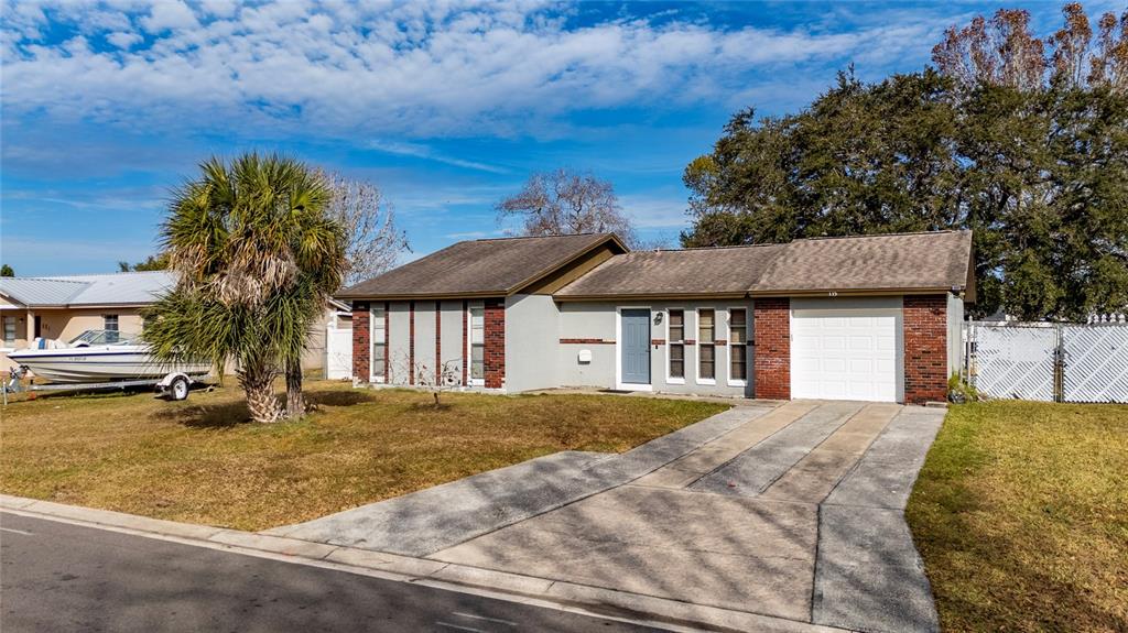 A single-story house with a brick and stucco exterior, a white fence, and a lawn — 115 TOLUCA DRIVE, KISSIMMEE, FL