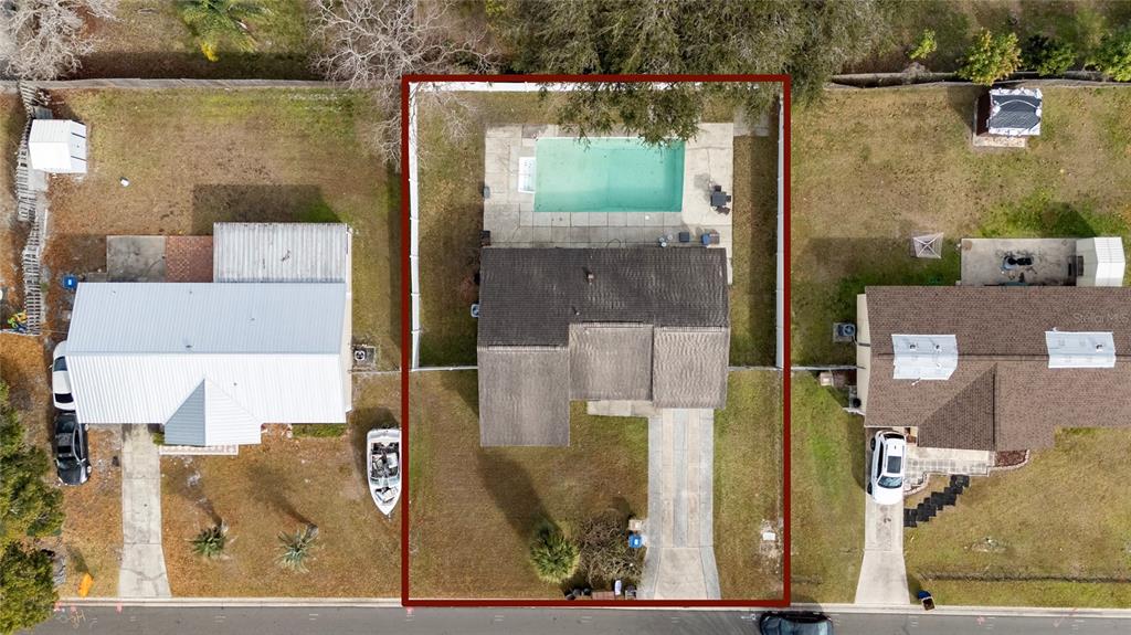 An empty room features vaulted ceilings with exposed wooden beams and dark wood-look flooring — 115 TOLUCA DRIVE, KISSIMMEE, FL