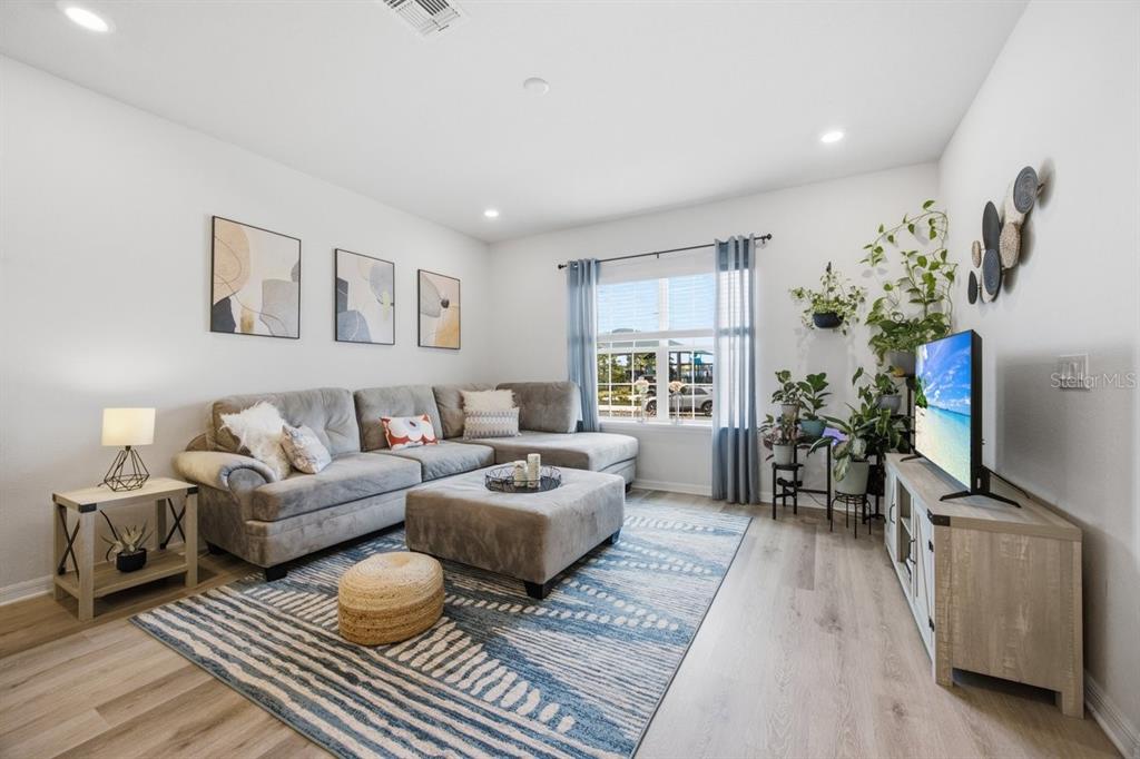 A living room with a gray sectional, area rug, television, and stairs to the upper level — 5813 MILLHOUSE WAY, ST CLOUD, FL