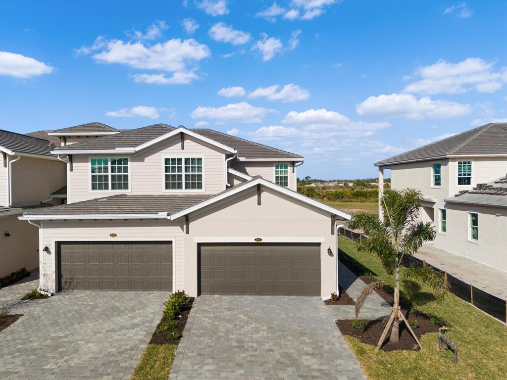 An exterior view of a two-story duplex with two garage doors and a paved driveway — 17585 BORACAY COURT UNIT 2-102, VENICE, FL