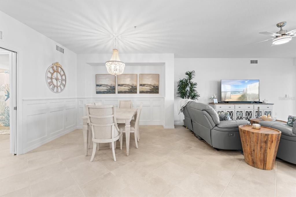 A dining area with a chandelier and a living room with gray furniture and tile floors — 17585 BORACAY COURT UNIT 2-102, VENICE, FL