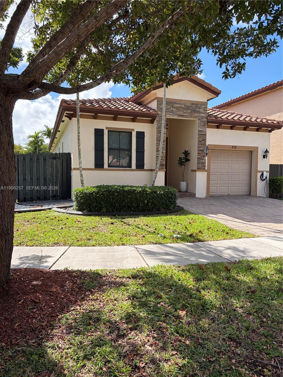 A single-story house with a stone-accented entryway, a garage, and a manicured front lawn — 470 SE 34TH TER, Homestead FL 33033, HOMESTEAD, FL