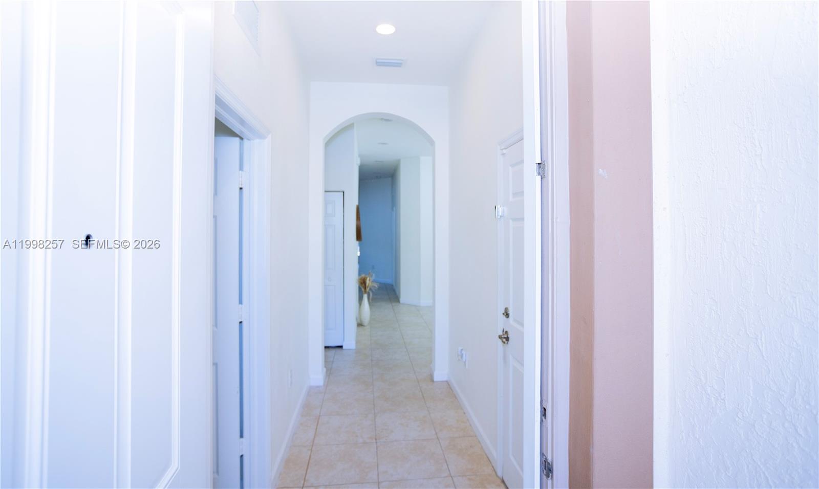 A bright hallway features white walls, tiled floors, and an arched entryway leading further inside — 470 SE 34TH TER, Homestead FL 33033, HOMESTEAD, FL