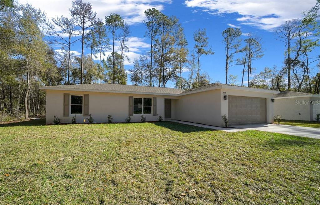 A single-story house with a beige exterior, a two-car garage, and a large front lawn — 8992 N LISA TERRACE, CITRUS SPRINGS, FL