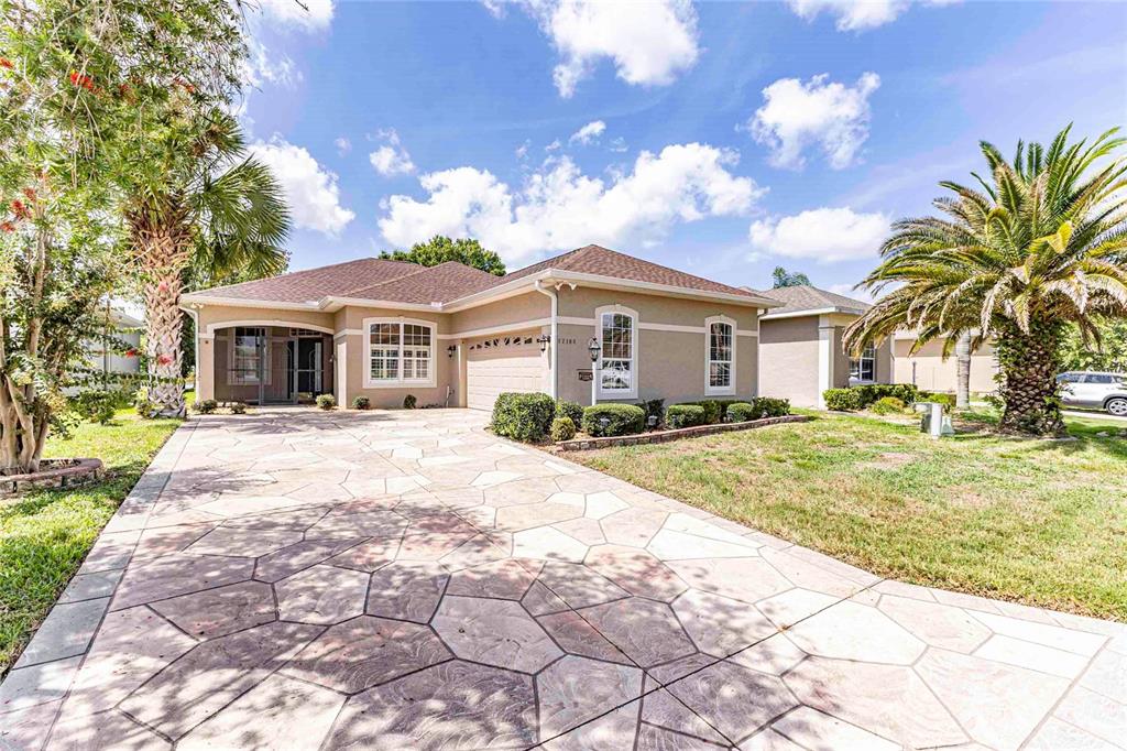 A single-story house with a stone-patterned driveway, a two-car garage, and palm trees — 12104 SE 178TH STREET, SUMMERFIELD, FL