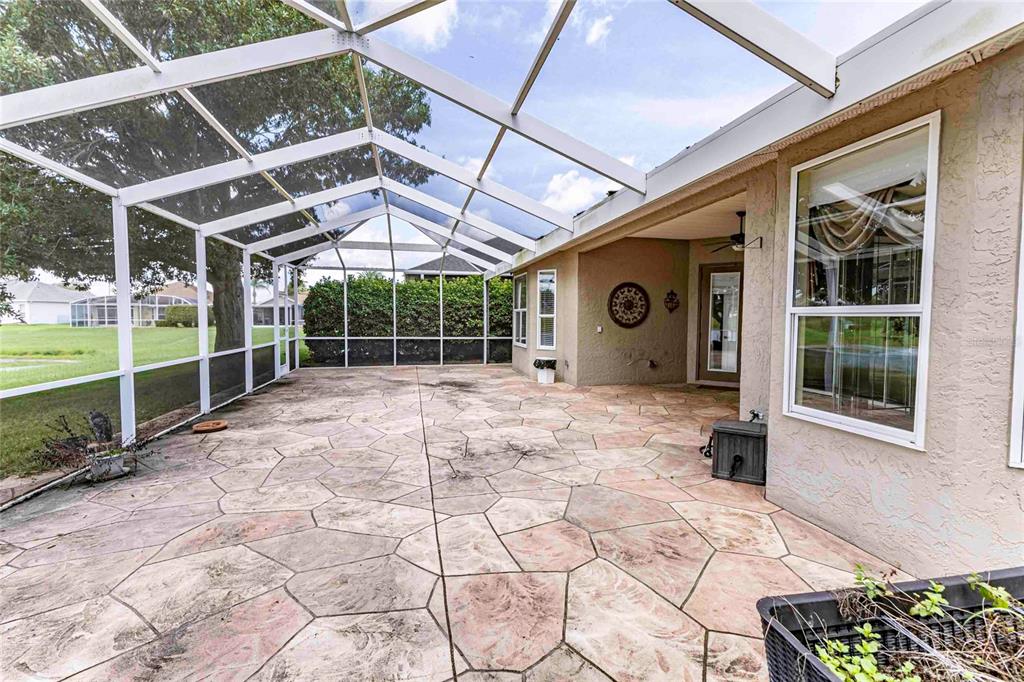 A screened-in patio features a stamped concrete floor and views of a grassy backyard — 12104 SE 178TH STREET, SUMMERFIELD, FL