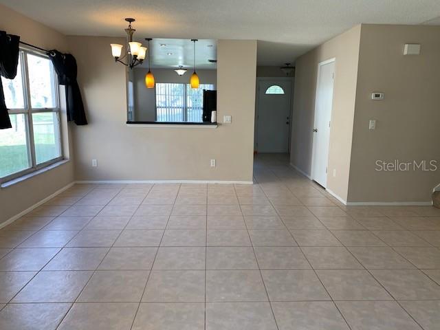 A dining area with tile flooring, a chandelier, and a pass-through window to the kitchen — 860 MAPLE FOREST DRIVE, ORLANDO, FL
