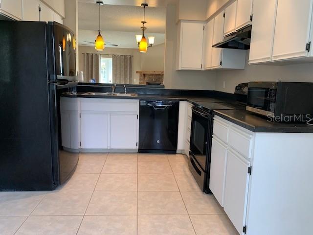 A kitchen features white cabinets, black appliances, and light-colored tile flooring — 860 MAPLE FOREST DRIVE, ORLANDO, FL