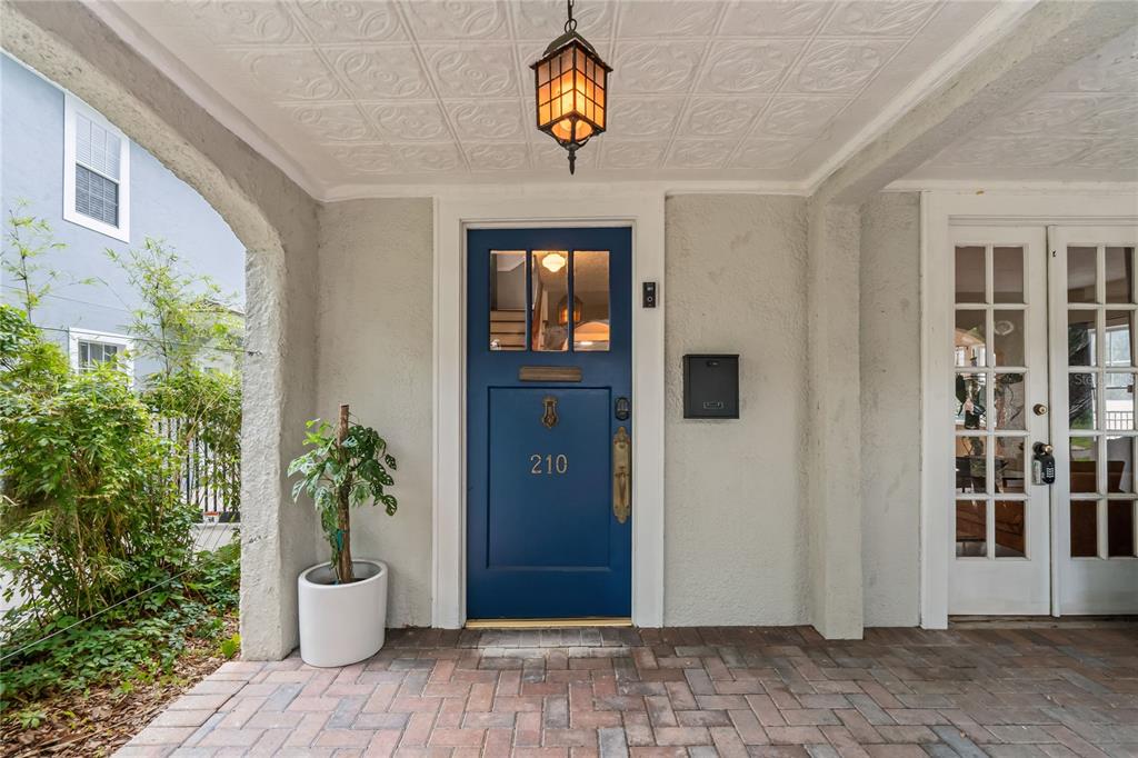 A blue front door with a house number sits on a brick porch under a ceiling — 210 PHILLIPS PLACE, ORLANDO, FL