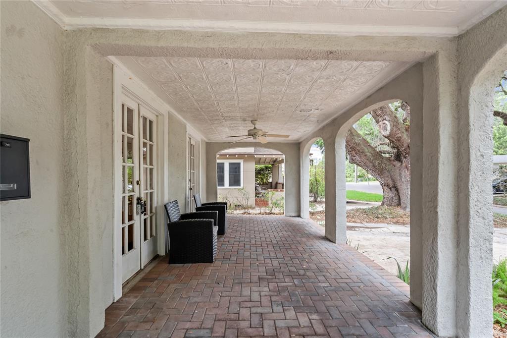 A covered porch features a brick floor, arched openings, and a patterned ceiling — 210 PHILLIPS PLACE, ORLANDO, FL