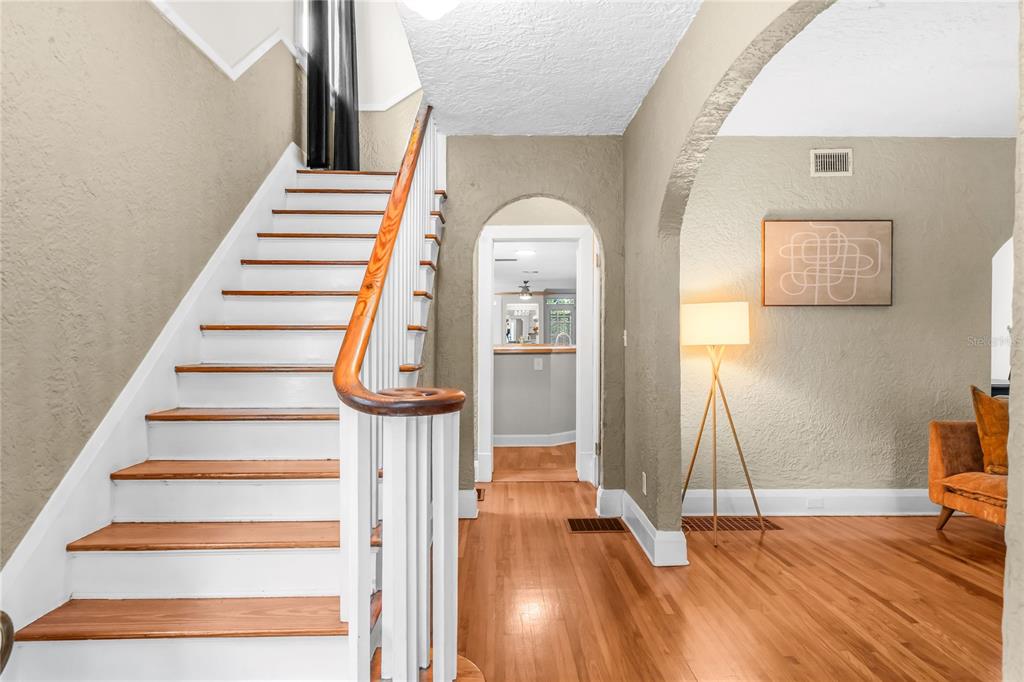 A staircase with wooden treads and white risers leads upward beside an arched doorway — 210 PHILLIPS PLACE, ORLANDO, FL