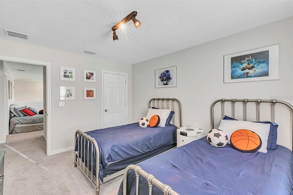 A bedroom features two twin beds with metal frames, blue bedding, and sports-themed decor — 1532 CAREY PALM CIRCLE, KISSIMMEE, FL