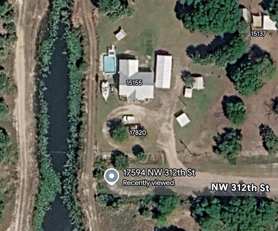 This is an aerial map view showing residential buildings, a driveway, and a nearby canal — 17594 NW 312TH STREET, OKEECHOBEE, FL