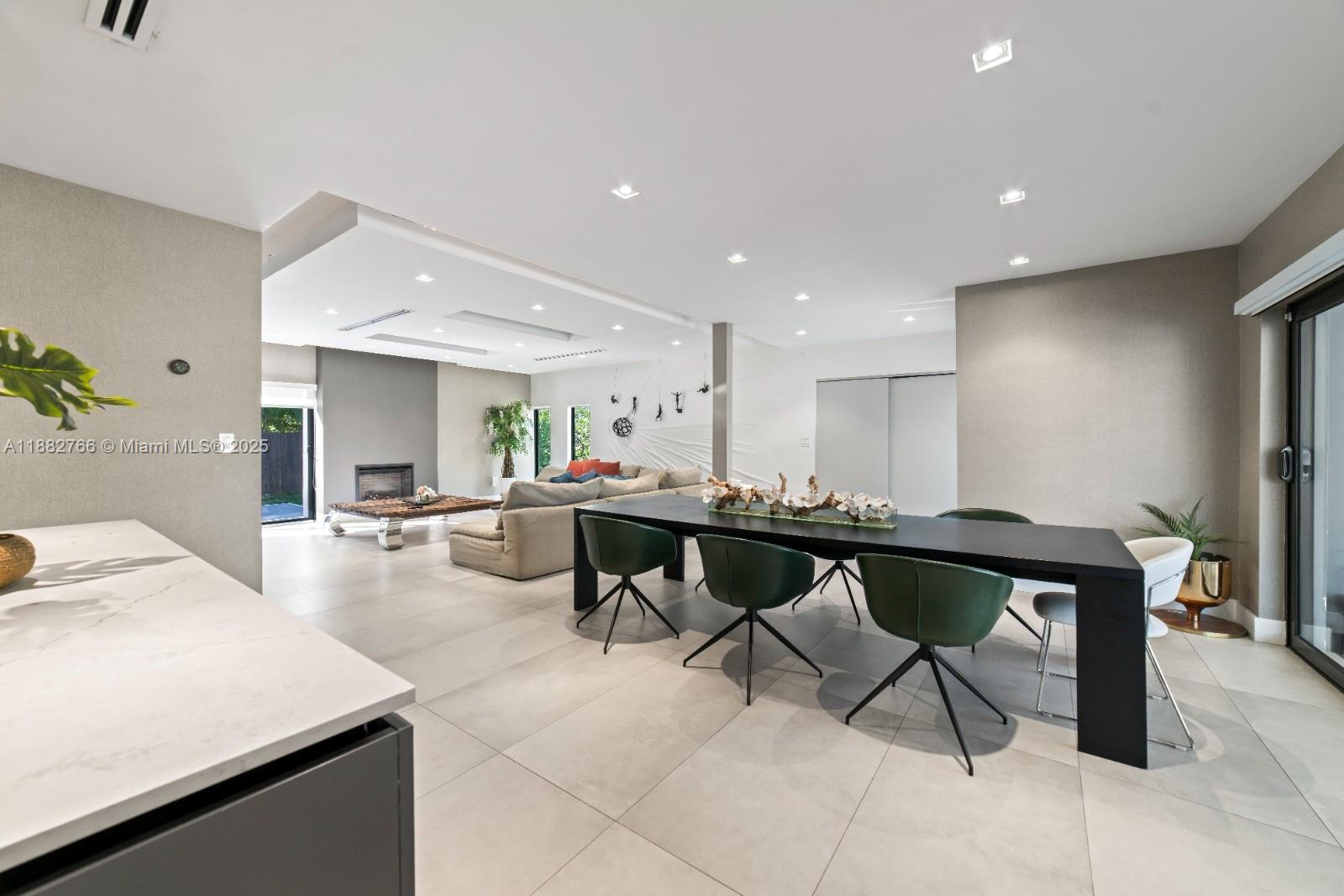 A modern open-concept living and dining area features tile floors, a fireplace, and dark furniture — 8365 SW 185th Ter, Cutler Bay FL 33157, CUTLER BAY, FL