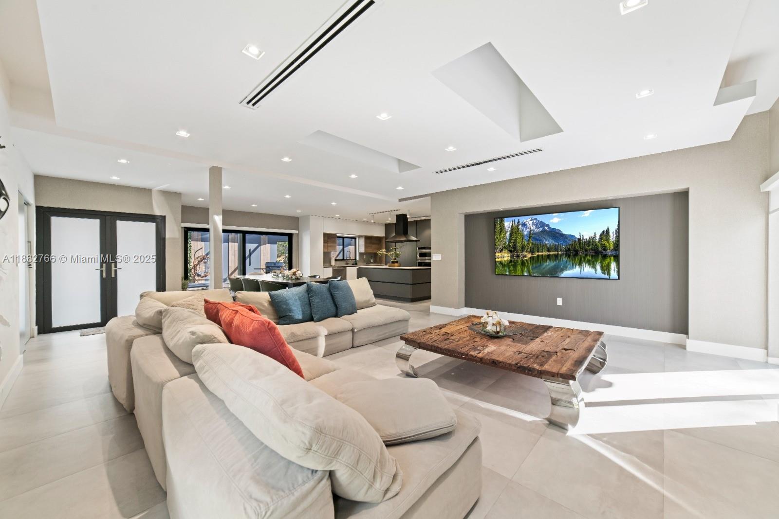 A modern open-concept living room features a large sectional sofa, a rustic coffee table, and a wall-mounted television — 8365 SW 185th Ter, Cutler Bay FL 33157, CUTLER BAY, FL