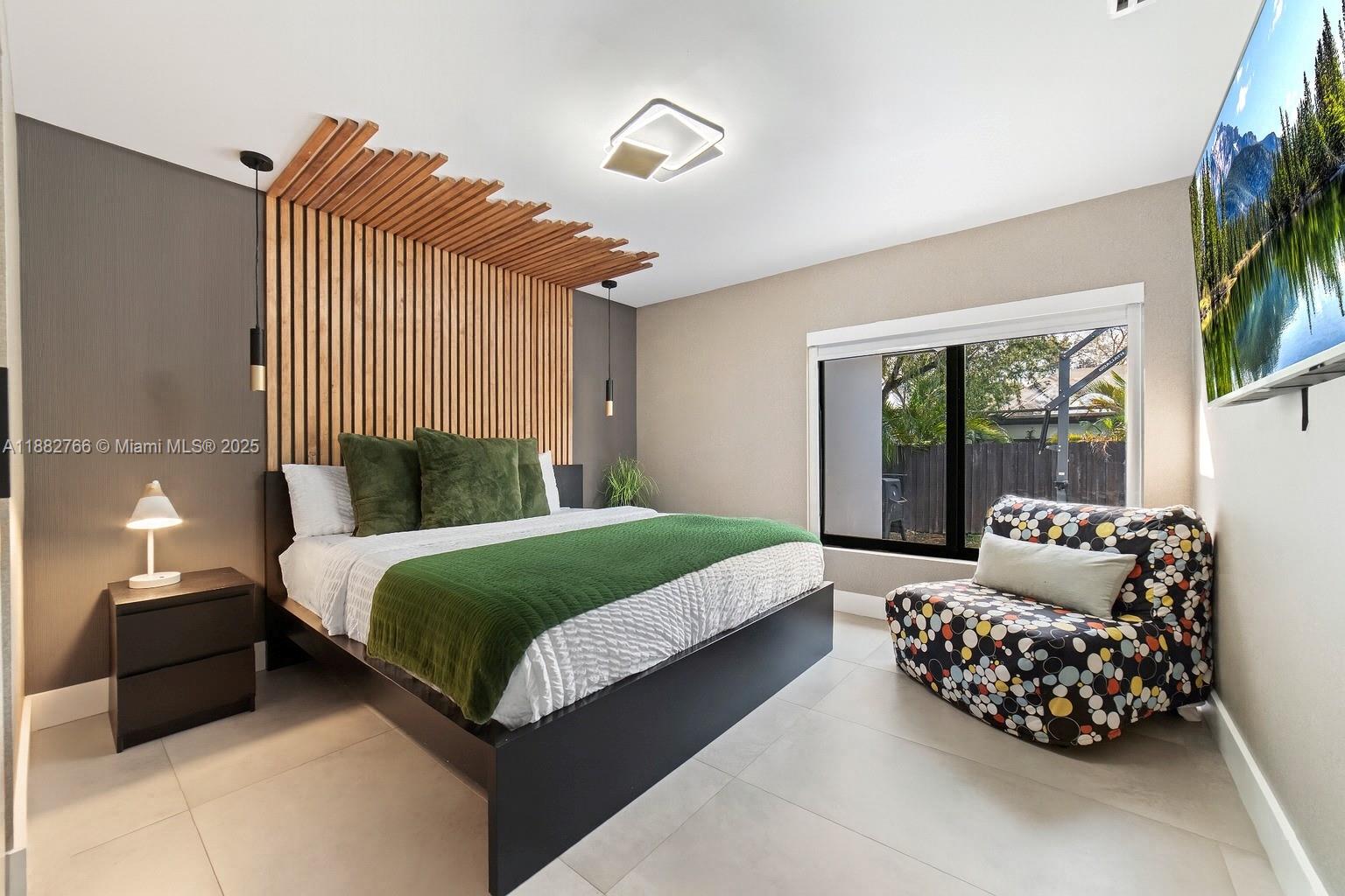A bedroom features a wood-slat headboard, a green bed runner, and a patterned armchair — 8365 SW 185th Ter, Cutler Bay FL 33157, CUTLER BAY, FL