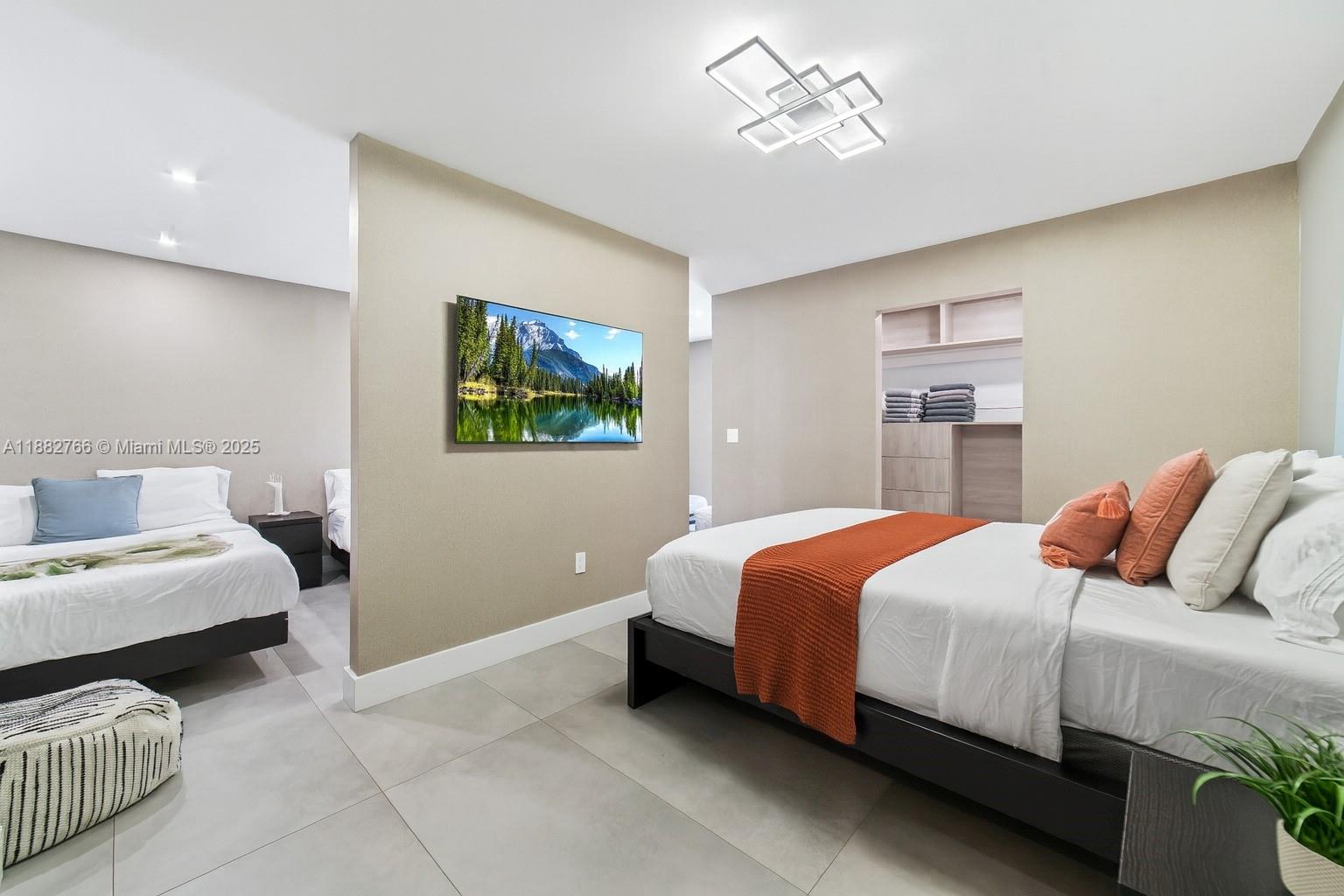A bedroom features two beds separated by a central wall with a mounted television — 8365 SW 185th Ter, Cutler Bay FL 33157, CUTLER BAY, FL
