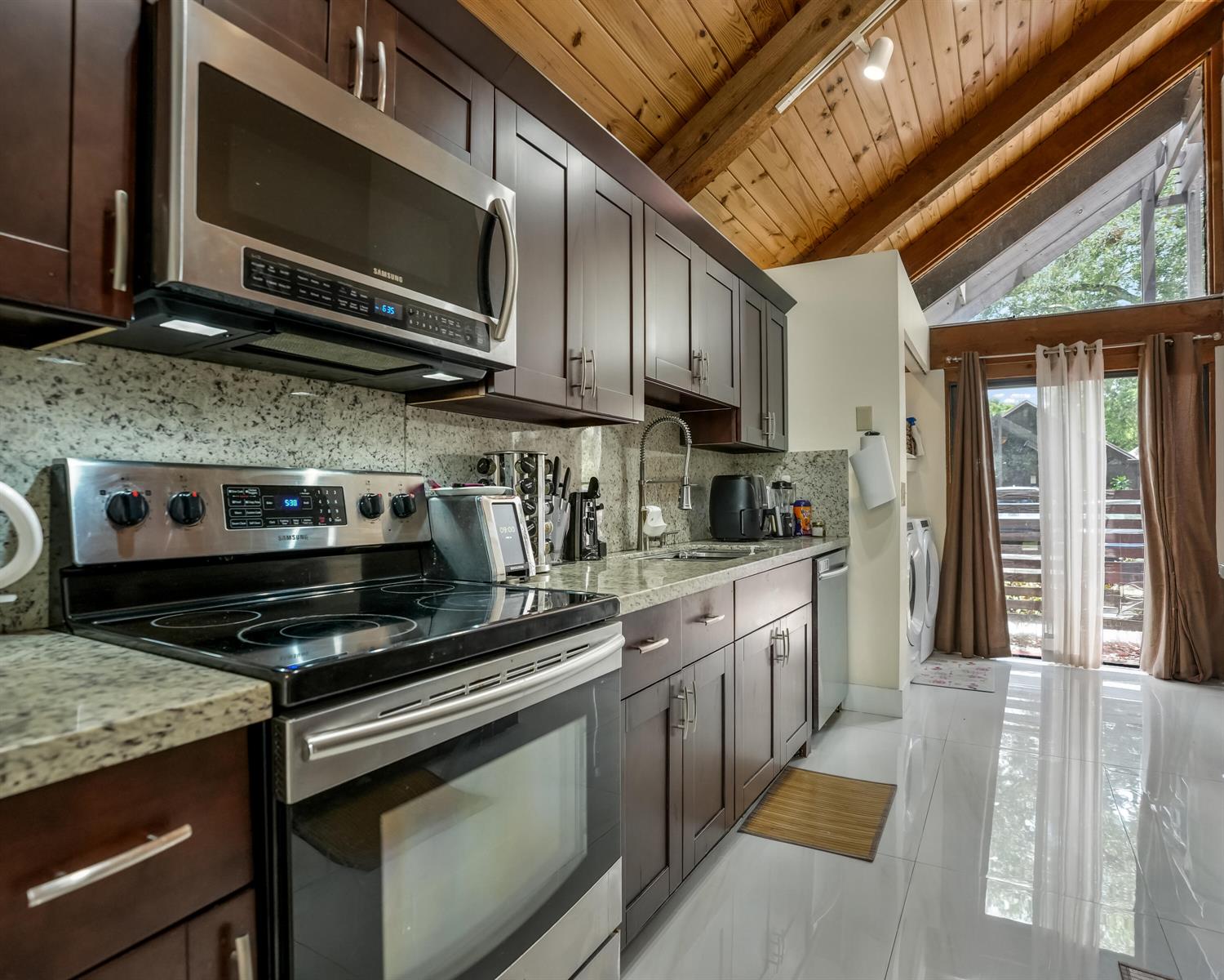 A kitchen features dark wood cabinets, granite countertops, stainless steel appliances, and a vaulted ceiling — 407 N University Drive, Plantation FL 33324, PLANTATION, FL