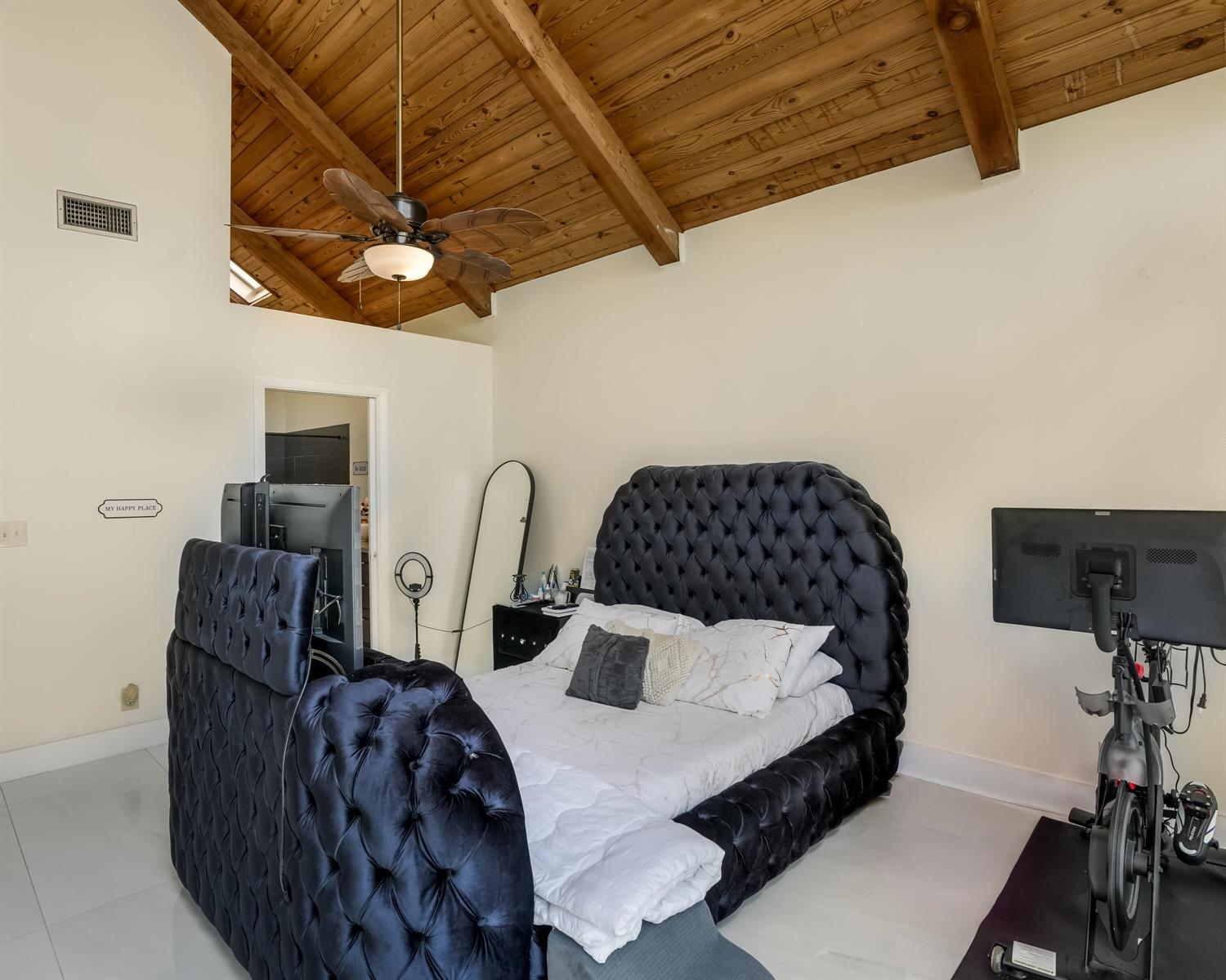 A bedroom features a tufted black velvet bed, vaulted wood-beam ceiling, and white tile floors — 407 N University Drive, Plantation FL 33324, PLANTATION, FL