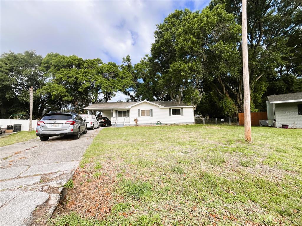 A single-story white house with a carport sits behind a large, grassy front yard — 121 MARIS COURT, LAKELAND, FL