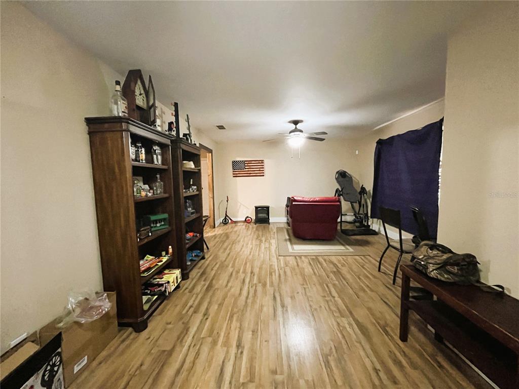 A living room features wood-look flooring, two tall wooden bookshelves, and a red recliner — 121 MARIS COURT, LAKELAND, FL