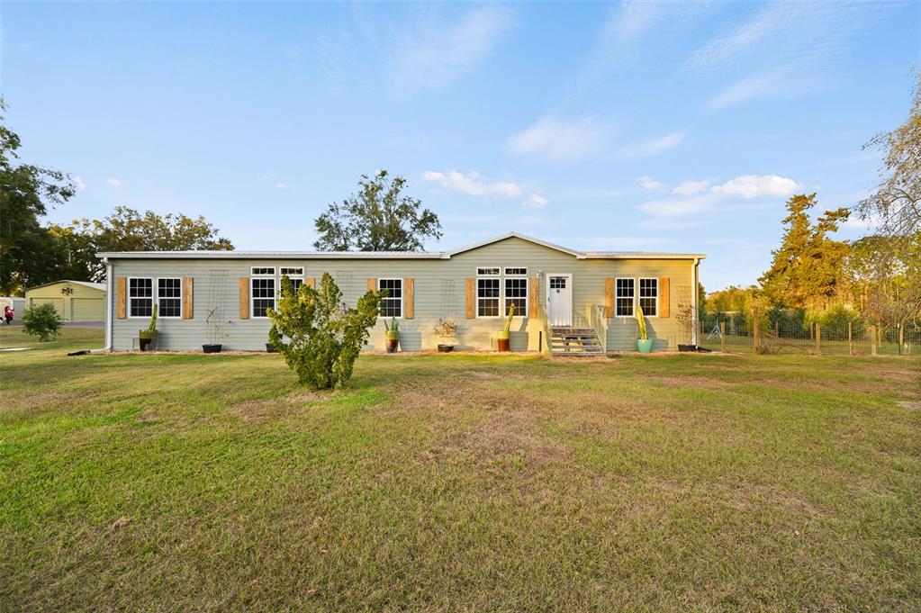 A single-story light green manufactured home sits on a large grassy lot — 22928 NW 102ND AVENUE, ALACHUA, FL