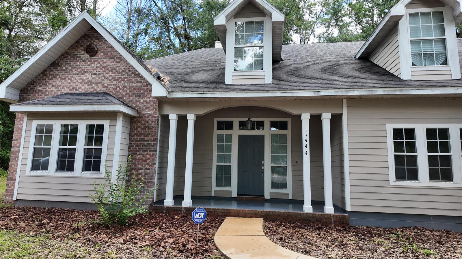 The exterior of a two-story house features a brick and siding facade with a covered porch — 11444 NW 18th Lane, Gainesville FL 32606, GAINESVILLE, FL