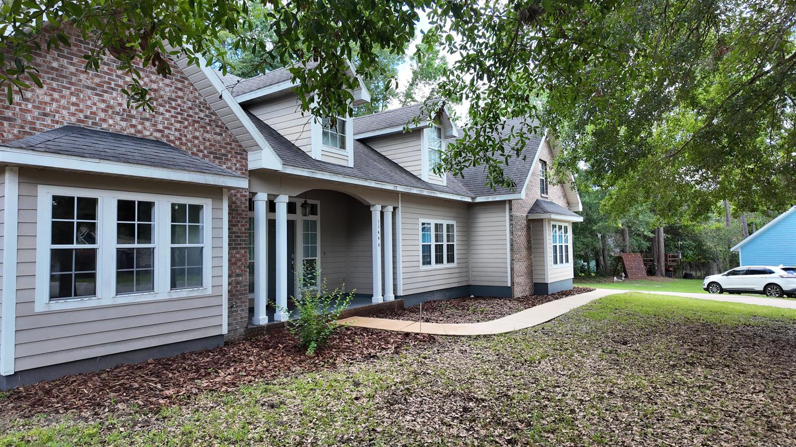 A two-story house with brick and beige siding features a covered porch and front walkway — 11444 NW 18th Lane, Gainesville FL 32606, GAINESVILLE, FL